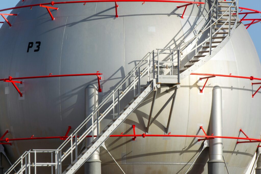 Large industrial storage tank with metal staircase and red railings, symbolizing progress.